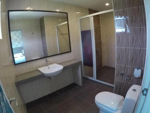 a bathroom with a toilet and a sink and a shower at HOTEL KAWAN BIDOR in Sungkai