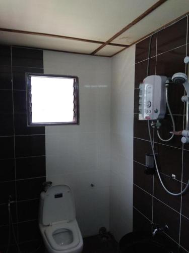 a bathroom with a white toilet and a window at MyDesaStay in Sekincan