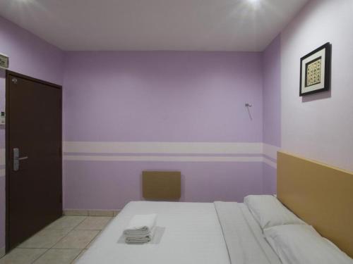 a room with a bed and a purple wall at Hotel Zamburger Sri Petaling in Kuala Lumpur