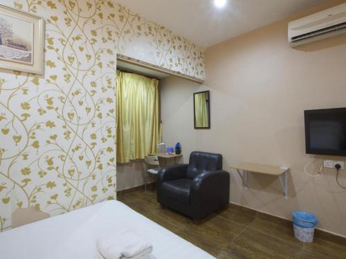 a room with a bed and a chair and a television at Hotel Zamburger Sri Petaling in Kuala Lumpur