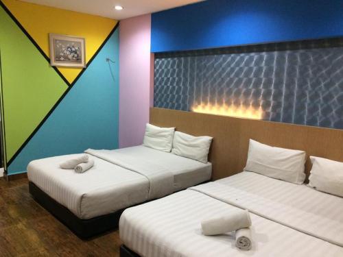 a room with two beds and a colorful wall at Hotel Zamburger Sri Petaling in Kuala Lumpur