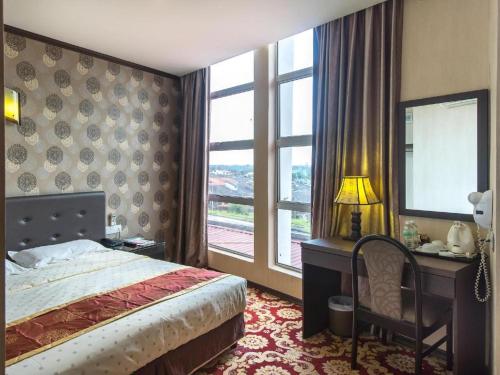 Un dormitorio con una cama y un escritorio y una ventana. en S Bee Hotel, en Johor Bahru