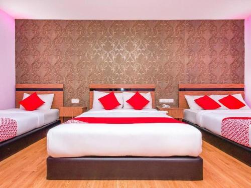 a bedroom with two beds with red pillows at Hotel Aromas Kulai in Johor Bahru