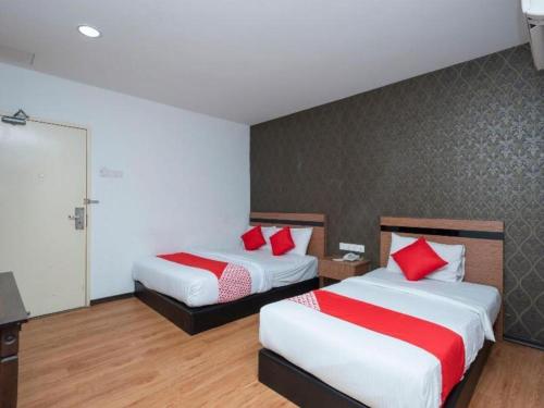 a hotel room with two beds with red pillows at Hotel Aromas Kulai in Johor Bahru