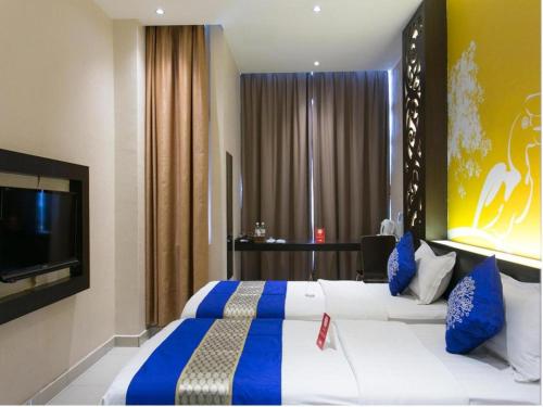 a hotel room with two beds and a flat screen tv at OYO 288 Sri Enstek Hotel in Sepang