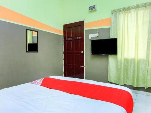 a bedroom with a bed and a flat screen tv at OYO 89684 Mawaddah Inn Stay in Tangkak