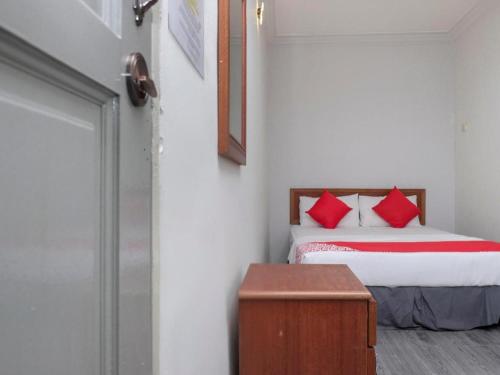 a bedroom with a bed with red pillows and a table at OYO 90120 MI Hotel Dungun in Dungun