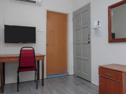 a room with a desk and a television and a door at OYO 90120 MI Hotel Dungun in Dungun