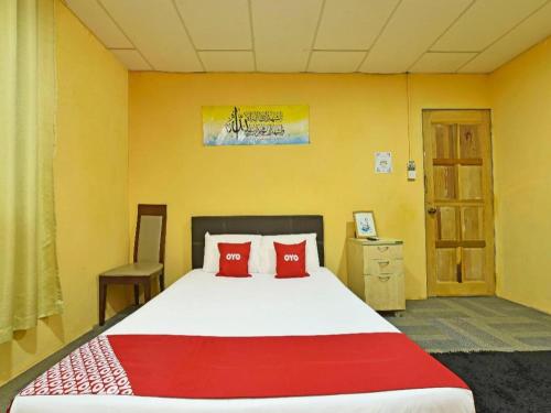 a bedroom with a large bed with red pillows at OYO 90535 Wakaf Bharu Inn in Kota Bharu