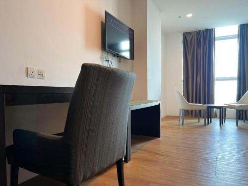 a room with a chair and a desk with a television at Cube Plus Signature Hotel OUG Kuala Lumpur in Kuala Lumpur