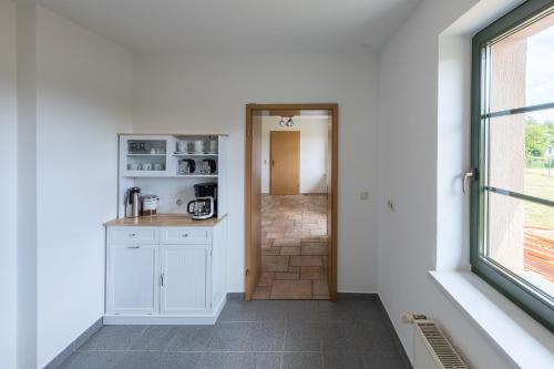 a kitchen with white cabinets and a window at Ferienhaus Wiesenquartier - eingezäuntes Grundstück und Platz für 10 Personen in Penkow