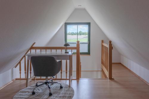 an office with a desk and a chair in a attic at Ferienhaus Wiesenquartier - eingezäuntes Grundstück und Platz für 10 Personen in Penkow