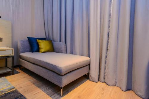 a chair sitting in front of a window with curtains at Echarm Hotel Guizhou Xingyi Jushan Avenue in Xiawutun
