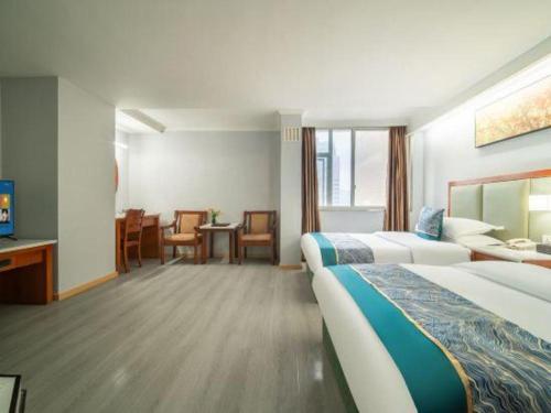 a hotel room with two beds and a table and chairs at Jun Hotel Guizhou Guiyang Yunyan District Yunyan Square in Guiyang