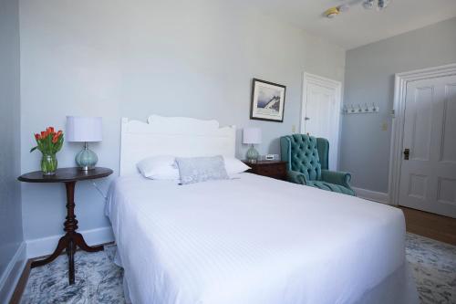 a bedroom with a white bed and a table and a chair at Queen Anne Inn in Annapolis Royal
