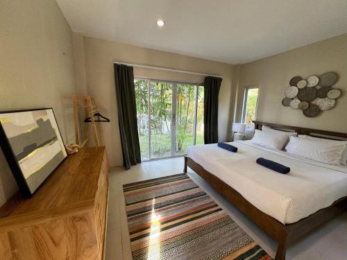 a bedroom with a large bed and a large window at Nai Thon villa with pool, garden, rooftop terrace in Ban Sakhu