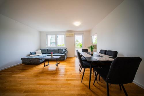 a living room with a couch and a table and chairs at Flex SelfCheckIns 169 - Zagreb - Loggia - Parking - 2 Bedroom in Zagreb