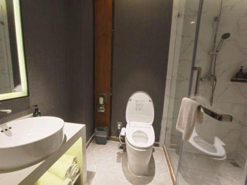 a bathroom with a toilet and a sink and a shower at Magnotel Shenyang Consulate Qingnian Street in Shenyang