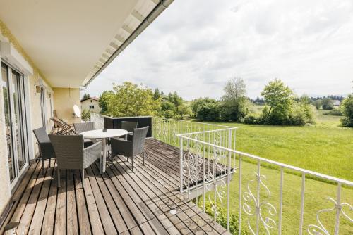 a deck with a table and chairs and a field at HEIMATEL - Ferienhaus Blümele in Scheidegg
