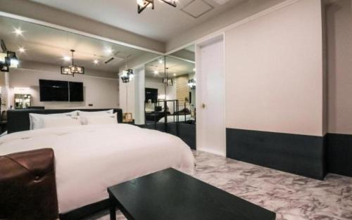 a bedroom with a large white bed and a table at Hotel Seowa in Gimhae