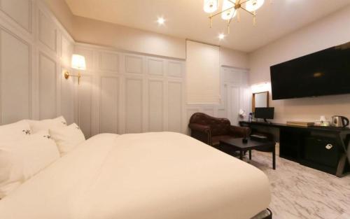 a bedroom with a large white bed and a desk at Hotel Seowa in Gimhae