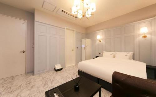 a bedroom with a large white bed and a couch at Hotel Seowa in Gimhae
