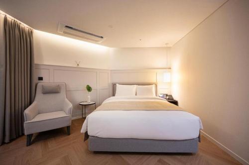a bedroom with a large bed and a chair at HOTEL D EDITION in Daejeon