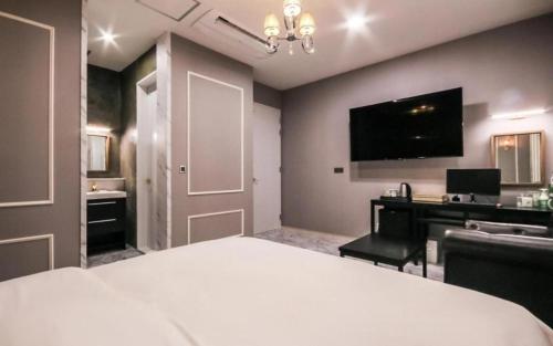 a bedroom with a bed and a desk and a television at Hotel Seowa in Gimhae