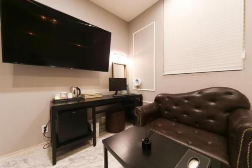 a living room with a couch and a desk with a television at Hotel Seowa in Gimhae