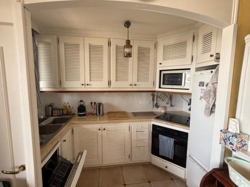 une cuisine avec des armoires blanches, un évier et un micro-ondes dans l'établissement Chez Sophie et Vincent, à Cogolin