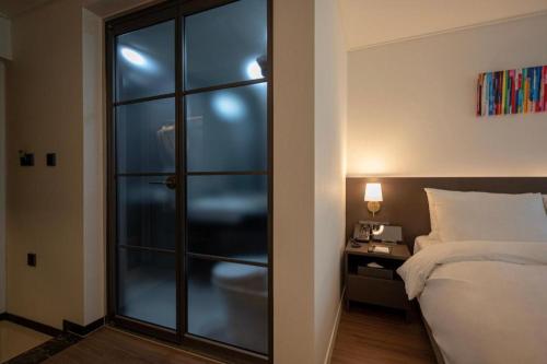 a bedroom with a bed and a glass door at HOTEL D EDITION in Daejeon