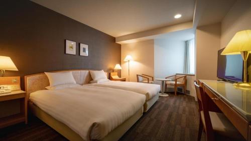 a hotel room with a bed and a flat screen tv at Air Terminal Hotel in Chitose