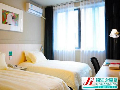 a hotel room with two beds and a window at Jinjiang Inn Luoyang Wangcheng Park Metro Station in Luoyang