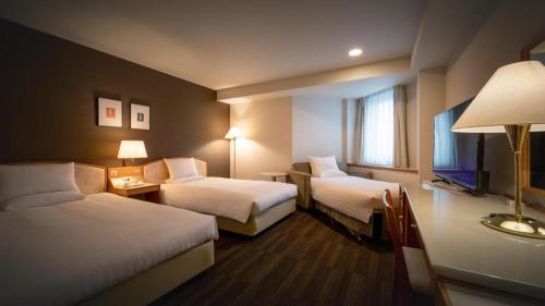 a hotel room with two beds and a window at Air Terminal Hotel in Chitose