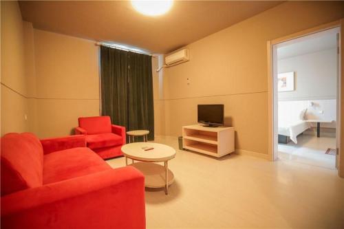 a living room with a red couch and a television at Jinjiang Inn Luoyang Wangcheng Park Metro Station in Luoyang