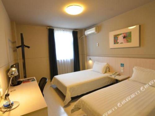 a bedroom with two beds and a desk and a window at Jinjiang Inn Luoyang Wangcheng Park Metro Station in Luoyang
