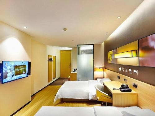 a hotel room with two beds and a flat screen tv at 7 Days Premium Xi'an Dayan Tower Xiaozhai Metro Station in Xi'an