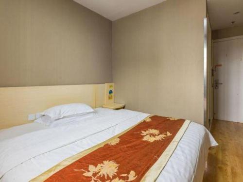 a bedroom with a large bed with a blanket on it at 7 Days Inn Qingdao Si Liu South Road in Qingdao