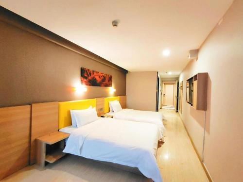 a hotel room with two beds with white sheets at 7 Days Premium Xi'an Dayan Tower Xiaozhai Metro Station in Xi'an
