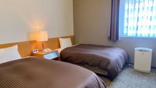 a hotel room with two beds and a window at Hotel Castle Plaza in Kobe