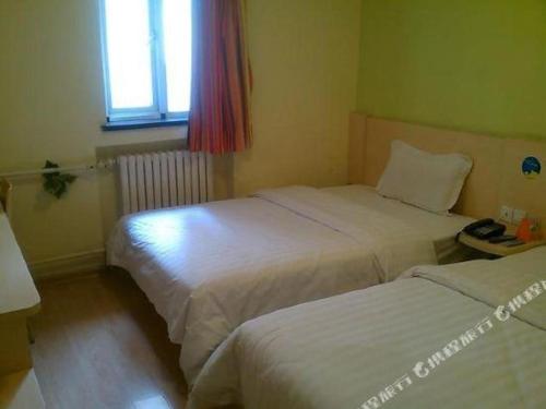 a hotel room with two beds and a window at 7 Days Inn Qingdao Si Liu South Road in Qingdao