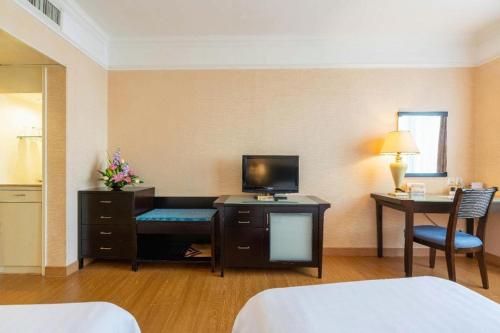 a hotel room with a television and a desk with a computer at Shantou Golden Gulf Hotel in Shantou