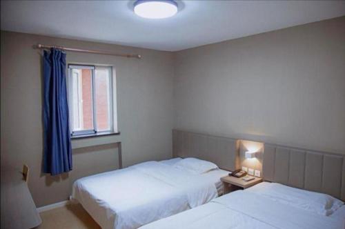 a hotel room with two beds and a window at 7 Days Inn Qingdao Si Liu South Road in Qingdao