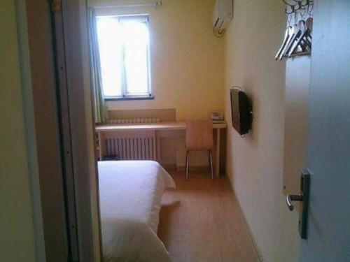 a room with a bed and a table and a window at 7 Days Inn Qingdao Si Liu South Road in Qingdao