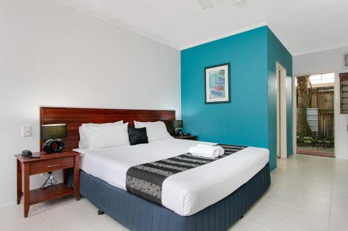 a bedroom with a large bed with a blue wall at Cairns City Palms in Cairns