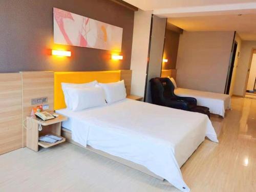 a hotel room with a large white bed and a chair at 7 Days Premium Xi'an Dayan Tower Xiaozhai Metro Station in Xi'an