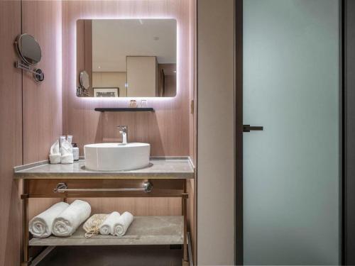 une salle de bain avec un lavabo, un miroir et des serviettes dans l'établissement Jinjiang Inn Nanjing Changjiang Bridge North Metro Station, à Taishan