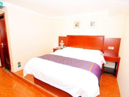 a bedroom with a white bed and a wooden headboard at GreenTree Inn Xian Longshouyuan Subway Station Business Hotel in Xi'an