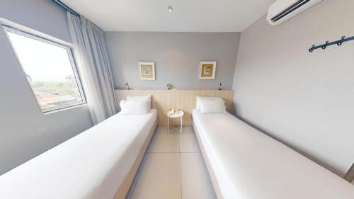 two beds in a room with a window at Country Inn in Johor Bahru