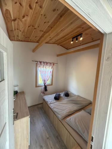 a bed in a room with a wooden ceiling at Domki Letniskowe Kosewo in Kosewo